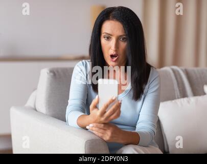 Sorpresa scioccata donna matura utilizzando il telefono cellulare Foto Stock