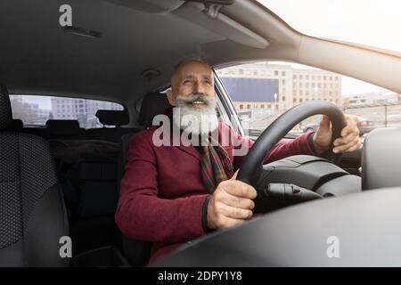 Bell'anziano uomo dai capelli grigi seduto all'interno di una nuova auto, che viaggia da solo Foto Stock