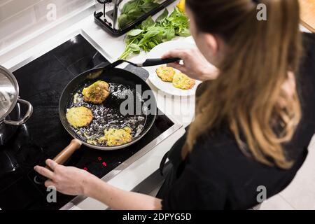Giovane donna svedese di charme che cucina a casa nella sua cucina, preparando cibo mediterraneo sano per la sua famiglia. Blogger di cibo giovane facendo cibo prepar Foto Stock