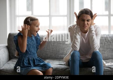 Primo piano su mamma sconvolto che copre le orecchie, problema con figlia rumorosa Foto Stock