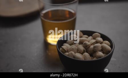 sidro di mele in vetro e pistacchi in ciotola nera su piano di cemento, foto ampia Foto Stock