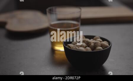 sidro di mele in vetro e pistacchi in ciotola nera su piano di cemento, foto ampia Foto Stock