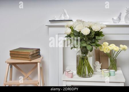 Bouquet di ranuncolo giallo e rosa bianca in un vaso di vetro sul tavolo bianco. Copia spazio Foto Stock