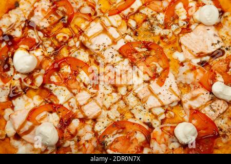 Deliziosa pizza di Philadelphia servita su un piatto di legno, ingredienti salsa Signature, mozzarella, salmone, gamberi, pomodori, salsa Teriyaki, formaggio Filadelfia su bianco. Poster promozionale pizzeria Foto Stock