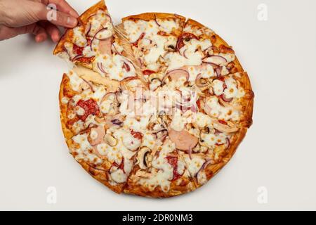 La mano dell'uomo prende una deliziosa fetta di pizza con Margarita o Margarita con mozzarella, UN uomo prende una fetta di pizza italiana e tira fuori un appetitoso formaggio fuso. Foto Stock