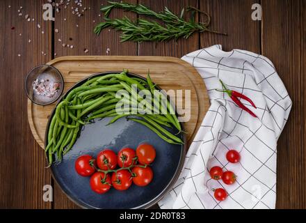 Pomodori, fagioli verdi in baccelli su sfondo di legno Foto Stock