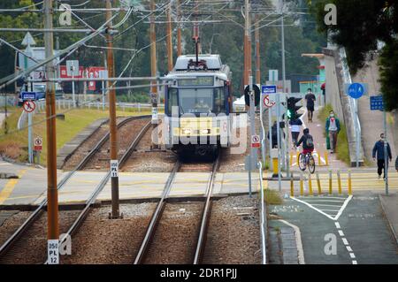 Treno leggero che si avvicina alla fermata Tsing Wun a Tuen Mun, Hong Kong con pista ciclabile e marciapiede Foto Stock