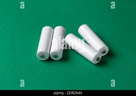 Batterie ricaricabili AAA bianche su sfondo verde. Posiziona per il testo. Concetto di energia verde. Foto Stock