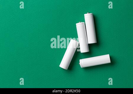 Batterie ricaricabili AAA bianche su sfondo verde. Posiziona per il testo. Concetto di energia verde. Foto Stock