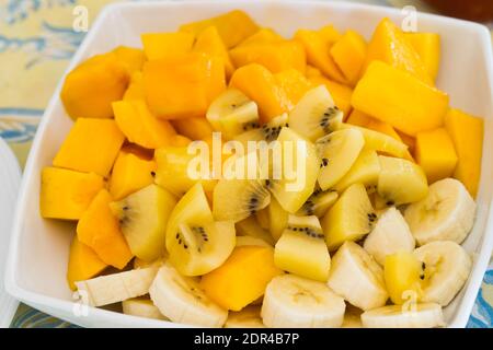 Grande piatto di frutta esotica fresca per colazione, mango, banane, kiwi dorato su un tavolo Foto Stock