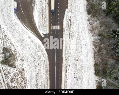 Strada pedonale che attraversa la foresta innevata con un grande camion, la vista dal drone Foto Stock