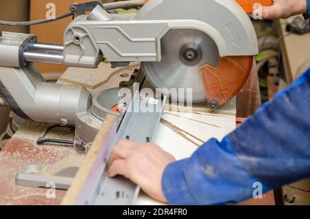 L'operatore taglia parte del telaio metallico utilizzando una sega circolare per il taglio dell'alluminio. Taglio del metallo. Macchina da taglio abrasiva Foto Stock