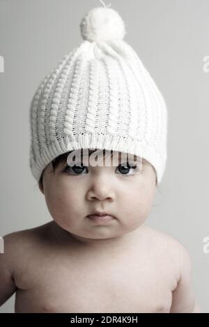 GRAN BRETAGNA / Inghilterra / Londra / Baby girl / 6-11 mesi /indossando maglia hat.on sfondo bianco Foto Stock