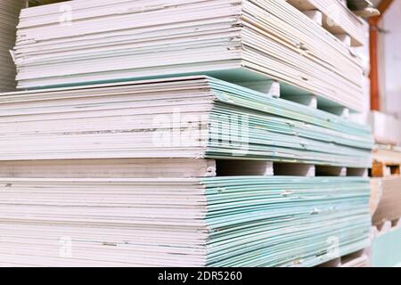 Pallet con cartongesso in lastre di cartongesso nel magazzino dell'edificio. Impilamento di pannelli in gesso bianco, cartongesso o cartongesso. Cartongesso Foto Stock