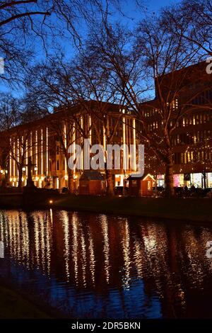 La strada dello shopping illuminata Königsallee nel centro di Düsseldorf a Natale con il riflesso dell'acqua nel canale della città. Foto Stock