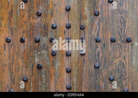 Primo piano di una porta in legno rustico dal design vintage con rivetti in metallo decorativi Foto Stock