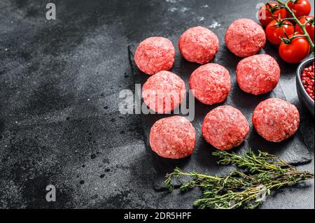 Polpette crude di manzo macinato. Sfondo nero. Vista dall'alto. Spazio di copia. Foto Stock