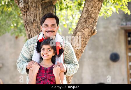 Padre indiano rurale con figlia che guarda la macchina fotografica Foto Stock