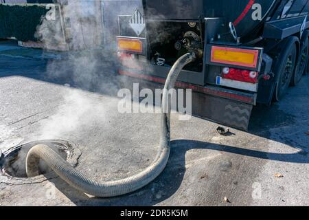 Scarico da una autocisterna con olio combustibile per gravità a un serbatoio sul terreno, quando il liquido è caldo, i vapori fuoriescono attraverso lo sfiato del serbatoio. Foto Stock