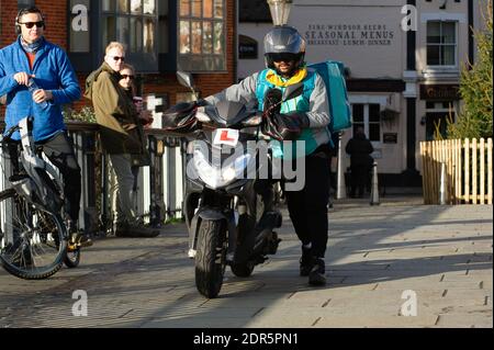 Eton, Windsor, Berkshire, Regno Unito. 20 Dicembre 2020. Un autista di Deliveroo spinge la sua moto sul ponte di Windsor da Eton. Dopo l'annuncio del governo di ieri sera, il Berkshire è entrato nel Covid-19 Tier 4. La gente era ancora fuori e circa questa mattina per le passeggiate e i caffè di take away. Credit: Maureen McLean/Alamy Live News Foto Stock