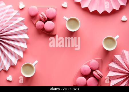 Stampa creativa in bianco e nero su carta a colori rosa. Maccheroni yummy e tre tazze di caffè. Ventilatori di carta piegati e cuori di zucchero. Foto Stock