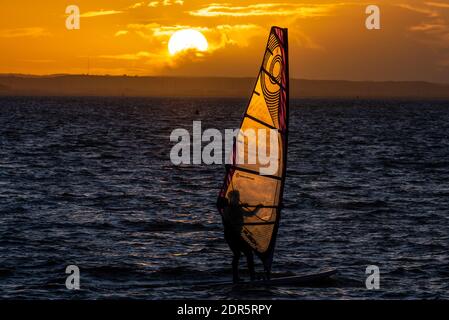 Chalkwell Beach, Southend on Sea, Essex, Regno Unito. 20 dicembre 2020. Il primo giorno di allarme COVID Tier 4 a Southend on Sea è finito luminoso ma freddo, con il sole tramontare dietro un windsurf fuori sull'estuario del Tamigi Foto Stock