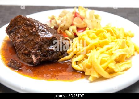 Guance di bue con tagliatelle e insalata Foto Stock