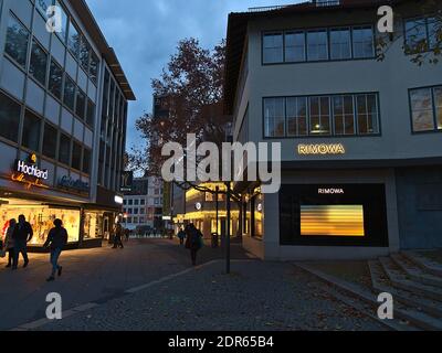 Via dello shopping Kirchstraße in centro con vetrine illuminate in serata e pedoni che passano durante la stagione natalizia. Foto Stock