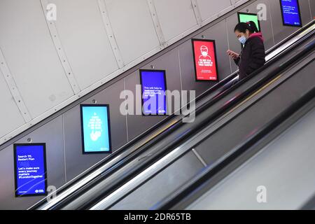 Una donna si trova su una scala mobile che si dirige verso la metropolitana alla stazione di Waterloo nel centro di Londra. Il primo ministro Boris Johnson ha annullato il Natale per quasi 18 milioni di persone in tutta Londra e nell'Inghilterra orientale e sud-orientale a seguito di avvertimenti da parte degli scienziati della rapida diffusione del nuovo coronavirus variante. Foto Stock