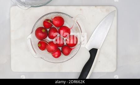 Ravanelli freschi organici su un piatto su fondo di marmo, piatto Foto Stock