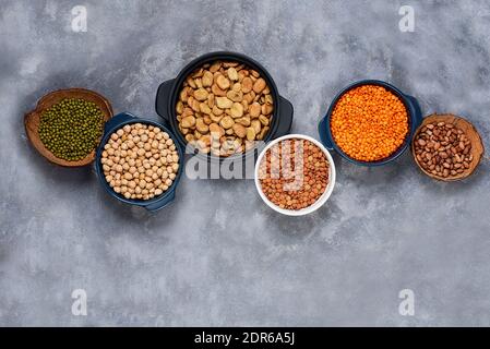 Vari assortimenti di legumi fagioli, ceci, lenticchie, piselli verdi. Concetto di alimentazione sana. Proteine vegetali. Calcestruzzo fondo copia spazio superiore vi Foto Stock