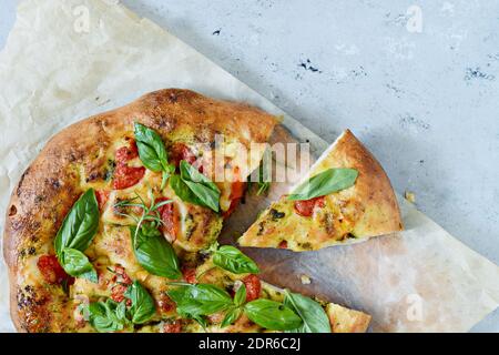 Pizza italiana fresca, focaccia con pomodori, pesto, aglio e rosmarino. Pane nazionale. Foto Stock