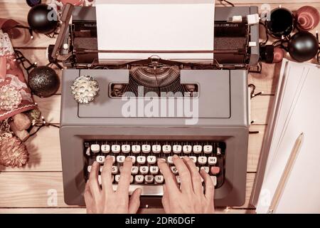 Atmosfera vintage. Digitare una lettera o un manoscritto su una vecchia macchina da scrivere durante il periodo natalizio. Coni di pino e decorazioni tutto intorno. Foto Stock