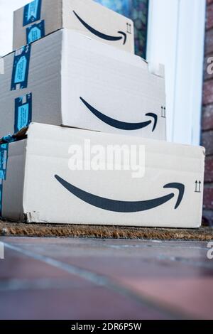 Le scatole di spedizione Amazon prime sono impilate e lasciate davanti della porta principale di casa Foto Stock