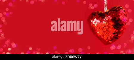 Paillettes rosse appesi cuore valentino su sfondo rosso. Foto Stock
