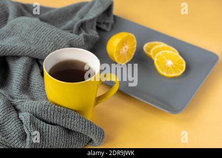 Tazza gialla di tè e limone a fette su piatto grigio. Colori alla moda 2021, vista dall'alto. Foto Stock