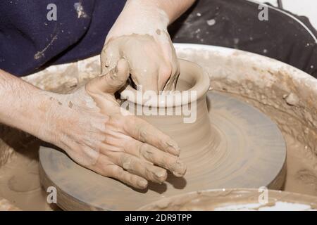 Mani che lavorano su una pentola di argilla. Vista laterale primo piano di mani artigiane che lavorano alla creazione di un vaso in ceramica. Foto Stock