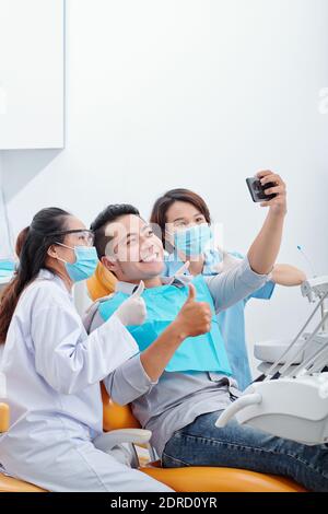 Paziente che fotografa con dentisti Foto Stock
