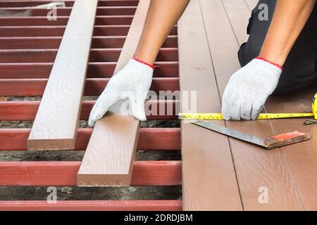 Lavoratore che installa pavimento di legno per patio Foto Stock