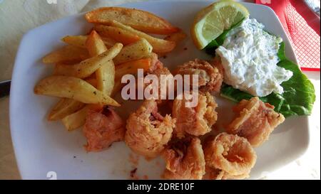 Calamari fritti con patatine fritte e salsa all'aglio su un piastra Foto Stock