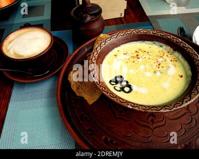 Zuppa cremosa decorata con aliveri in ciotola di ceramica e un tazza di caffè Foto Stock