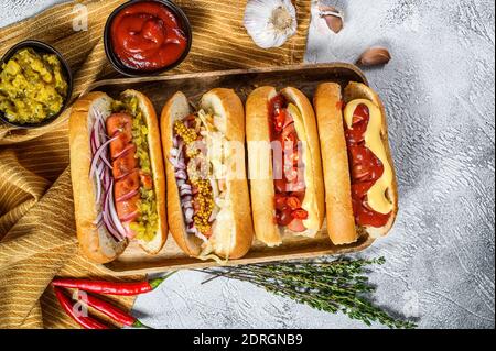 Hot dog completamente carico con condimenti assortiti su un vassoio deliziosi hot-dog con salumi di maiale e manzo. Sfondo bianco. Vista dall'alto. Foto Stock