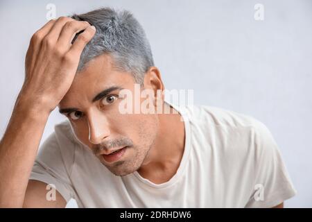 Uomo stressato con capelli grigi su sfondo chiaro Foto Stock