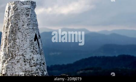 Escursione pomeridiana che raggiunge la cima del palo con il numero 11, situato sulla cima di un sentiero escursionistico con montagne in lontananza e un cielo nuvoloso scuro Foto Stock