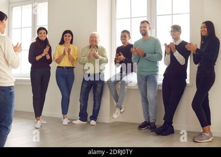 Gruppo di persone felici che si aggrappano le mani, ringraziando l'oratore o l'allenatore per un interessante workshop Foto Stock