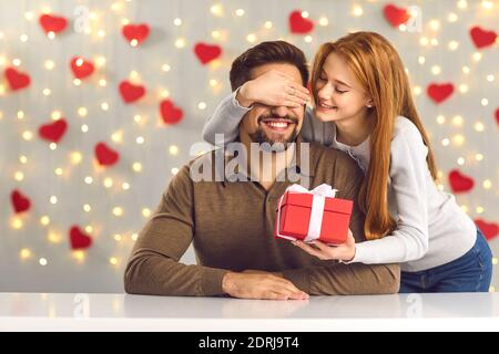 Felice giovane uomo che ottiene presente dalla sua ragazza amorevole sopra San Valentino Foto Stock