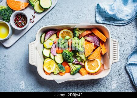 Verdure crude tritate - patate dolci, zucchine, broccoli e carote in un arrosto di piatto. Cottura delle verdure per la cottura in forno. Cucinare sano fo Foto Stock