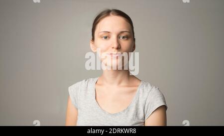 Abbastanza sorridente gioiosamente femmina con capelli forti, vestito casualmente, guardando con soddisfazione alla macchina fotografica, essendo felice. Studio di un bel Be Foto Stock