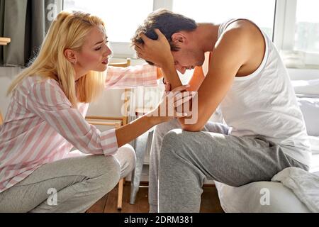 donna gentile sostiene suo marito a casa, donna hanno parlare con l'uomo seduto con la testa piegata, in camera da letto Foto Stock