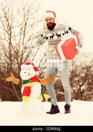 Sogni. Felice hipster pronto per natale. vacanze inverno. un maglione pesante a basse temperature. santa uomo dare presente all'esterno. l'uomo barbuto costruire pupazzo di neve. stagione invernale attività. Auguri di Buon Natale. Foto Stock